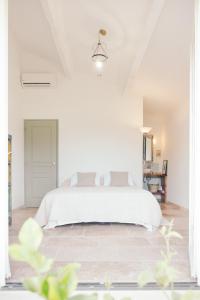 a white bedroom with a white bed in a room at Le jardin du Castillon in Paradou