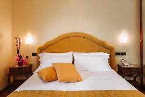 1 dormitorio con 1 cama grande con sábanas y almohadas blancas en Grand Hotel Excelsior, en Chianciano Terme