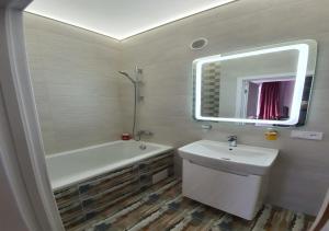 La salle de bains est pourvue d'un lavabo, d'une baignoire et d'un miroir. dans l'établissement Lux New Apartment 2019, à Kharkov