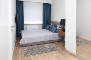 a bedroom with a bed with blue curtains and a window at Apartament Silva View in Hel