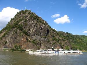 a white boat on the water near a mountain at Gaststätte Marktstübchen in Bornich