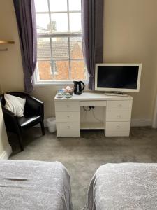 a bedroom with a desk with a television and a chair at The Victoria in Saltburn-by-the-Sea