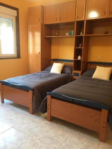 1 dormitorio con 2 camas y ventana en Pisos Turísticos Muxía- Teresa Barros -bajo-, en Muxía