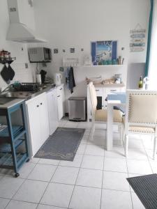 uma cozinha com armários brancos e uma mesa e cadeiras em Le Rumain em Hengoat