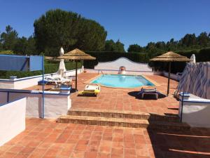 a swimming pool with chairs and umbrellas in a yard at Ninho das Perdizes - Monte Novo in Cercal