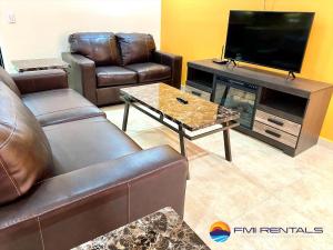 een woonkamer met lederen meubels en een flatscreen-tv bij Linda Vista 513 in Puerto Peñasco