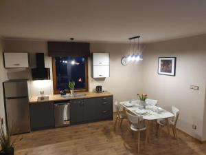 kuchnia i jadalnia ze stołem i krzesłami w obiekcie Apartamenty i Domki Mierzeja w Sztutowie