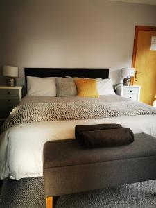 um quarto com uma cama grande e um repousa-pés em frente em The Tree-house B&B em Ballymena