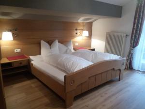1 cama con sábanas blancas y almohadas en una habitación en Gästehaus Zunterer en Wallgau