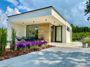 a modern house with purple flowers in the yard at Leśny Apartament - Shuuumi Las in Chmielno