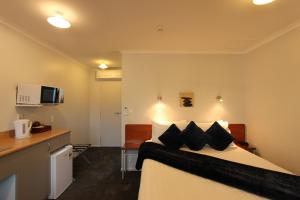 um quarto de hotel com uma cama com almofadas pretas em BK's Magnolia Motor Lodge em Whanganui