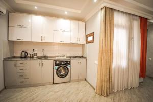 a kitchen with white cabinets and a washing machine at Sunrise Apartment in Batumi