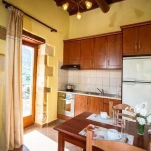 - une cuisine avec des placards en bois, une table et une table dans l'établissement Luxurious Stone Apartment 2, à Kerá