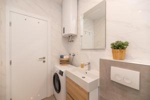 a white bathroom with a sink and a mirror at Apartman Ružica in Pučišća