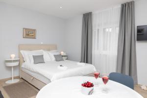 a bedroom with a bed and two tables with wine glasses at Apartman Ružica in Pučišća