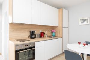 a small kitchen with white cabinets and a table at Apartman Ružica in Pučišća