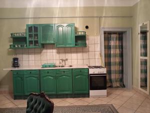 a kitchen with green cabinets and a stove at Rokoko Apartman in Abádszalók