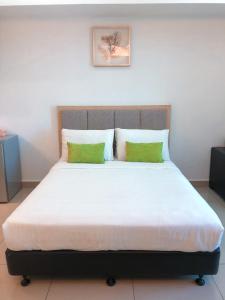 a bedroom with a large bed with two green pillows at Agrima Studio Apartment in Kota Bharu