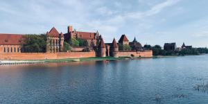 a castle sitting on the side of a body of water at Castle Apartments Malbork in Malbork