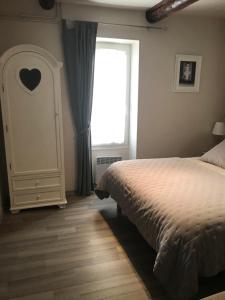 Schlafzimmer mit einem Bett und einem Fenster in der Unterkunft Au cœur de Céreste in Céreste