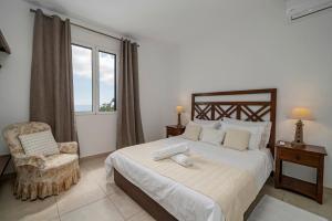 Un dormitorio con una cama y una silla y una ventana. en Villa Amelia, en Caniço 8 fotos más