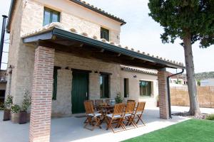 um pátio com cadeiras e uma mesa em frente a uma casa em Casa Clotilde em Alcañiz