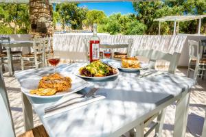 a table with plates of food and a bottle of wine at Coralli Seaside Resort in Livadakia