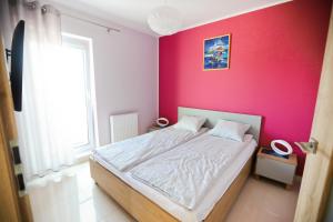 a bedroom with a bed with a pink wall at M&K Apartamenty - Marynarski in Gdańsk