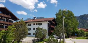 a white building with trees and mountains in the background at Alpina Inzell Wohnung 454 in Inzell