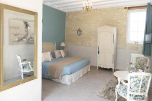 um quarto com uma cama, um espelho e uma cadeira em Les Pérelles em Saint-Vigor-le-Grand