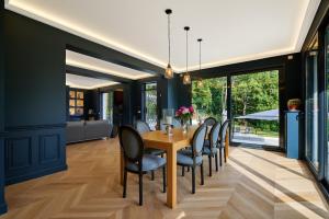 een eetkamer met een houten tafel en stoelen bij LA VILLA AUBIN belle demeure avec vue sur Paris in Montmorency