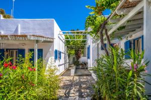 a path between two white houses with flowers at Coralli Seaside Resort in Livadakia