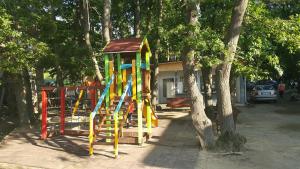 a playground with a slide in a park with trees at Ваканционно селище СБХ in Shkorpilovtsi