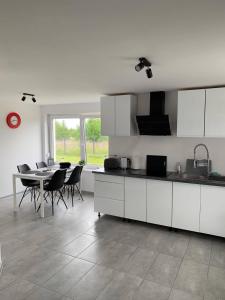 a kitchen with white cabinets and a table and chairs at Apartamenty "Marynarska " Rusinowo in Rusinowo