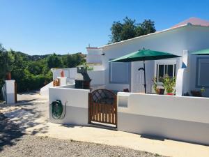 ein weißes Haus mit einem Tor und einem Regenschirm in der Unterkunft Quinta dos Netos in Tavira