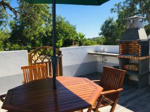 Ein Holztisch und Stühle mit einem Sonnenschirm auf einer Terrasse in der Unterkunft Quinta dos Netos in Tavira
