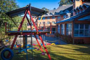 a playground in a yard next to a building at Hotel Renascença in Gramado