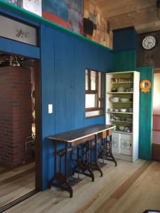 a dining room with a table and a blue wall at 一棟貸し宿bochi-bochi in Komagane