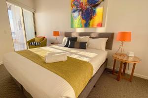 a bedroom with a bed, desk, lamp, and bedspread at Waves Maroochy River in Maroochydore