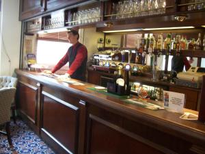 a man standing behind a counter in a bar at Elstead Hotel in Bournemouth