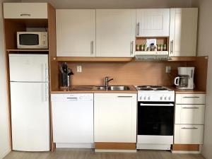 Una cocina con gabinetes blancos, un fregadero y una estufa. en Vuorsa 1 A 2, en Saariselkä 18 fotos más