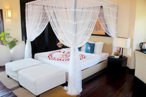 a bedroom with a white bed with a canopy at Poshanu Boutique Resort in Mui Ne