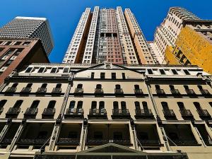 a tall white building with two tall buildings at Accommodation Sydney - Pitt Street in Sydney