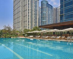 einen Pool mit Stühlen, Sonnenschirmen und Gebäuden in der Unterkunft Grand Hyatt Manila in Manila