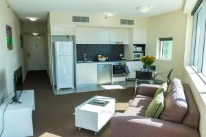 a living room with a couch and a kitchen at Evolution Apartments in Brisbane