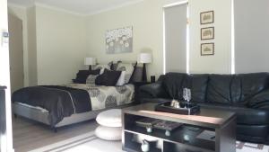 a living room with a bed and a black leather couch at Modern Self Contained Apartment in Riverhead in Riverhead