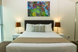 a bedroom with a large white bed with two lamps at Evolution Apartments in Brisbane