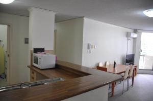 a kitchen with a counter with a microwave and a table at Accommodation Sydney City Centre - 2 Bedroom Apartment with Balcony on Top Floor in Sydney