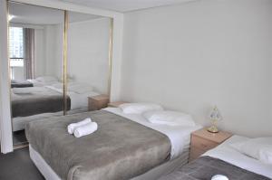 a hotel room with three beds with towels on them at Accommodation Sydney - Kent Street Sydney CBD Top floor 2 bedroom apartment with balcony in Sydney