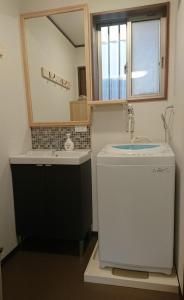 La salle de bains est pourvue d'un lavabo et d'un miroir. dans l'établissement 桃山ゲストハウス おかだ, à Kyoto